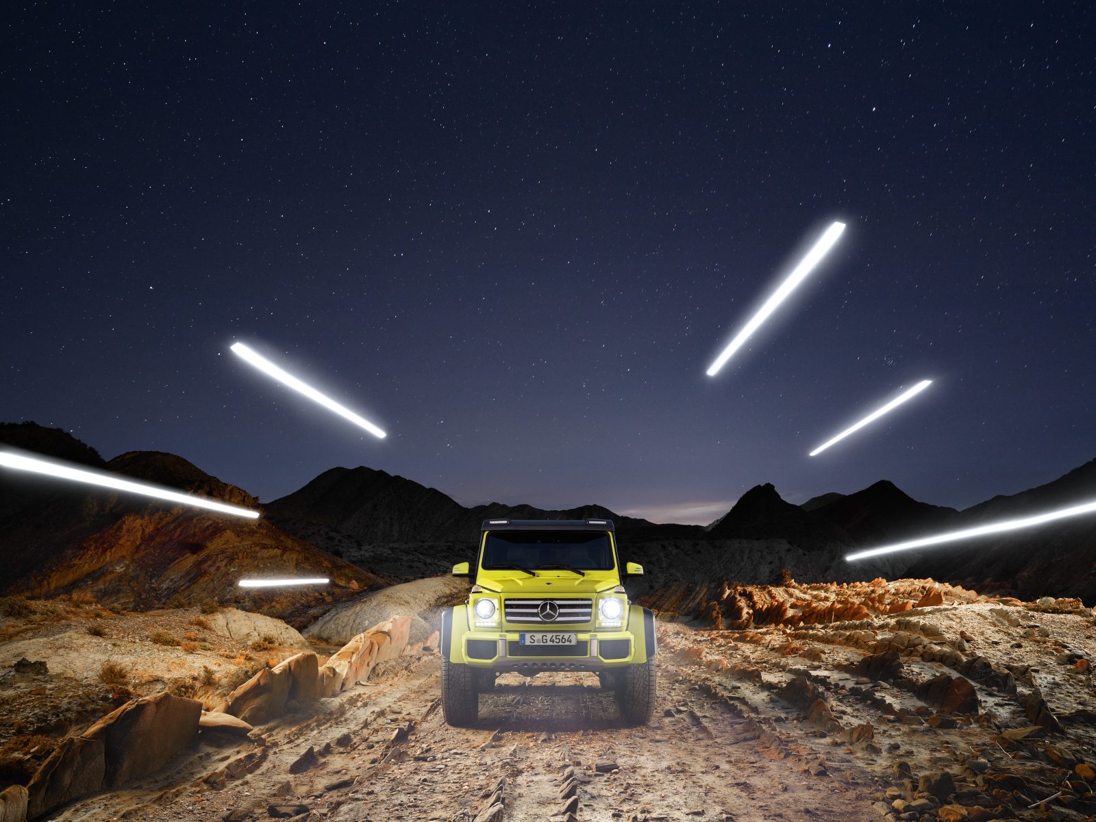 A neon green SUV on a rocky terrain at night, surrounded by futuristic streaks created with drone light painting, with mountains rising in the background.