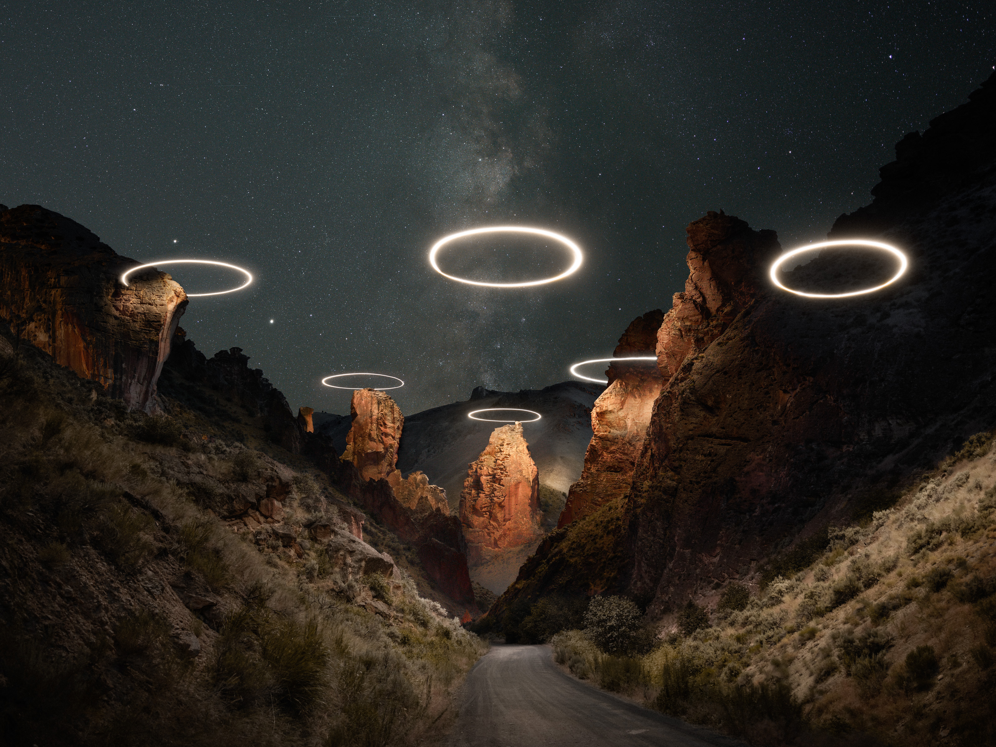 Glowing rings float above rocky canyon formations at night under a starry sky, creating a futuristic nighttime landscape photography scene.
