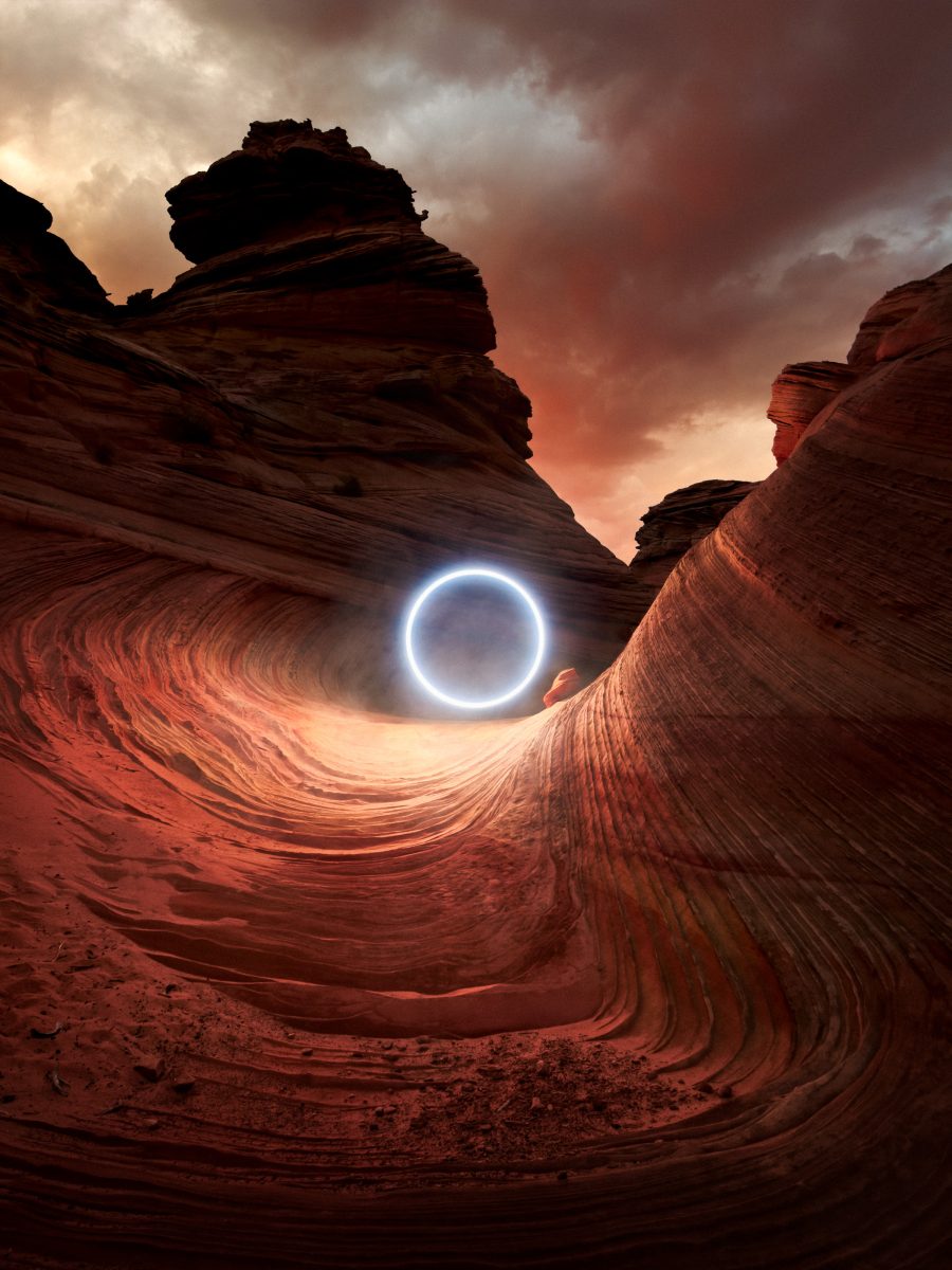 A futuristic glowing ring floats in a red rock canyon at sunset, under dramatic, cloudy skies—captured by a skilled photographer.