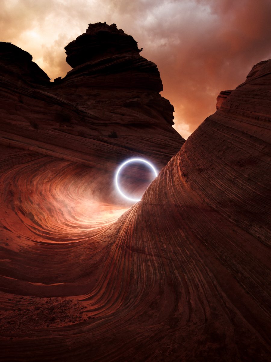 A glowing orb, created through drone light painting, floats in a dramatic red rock canyon with swirling, textured sandstone under a cloudy sky.