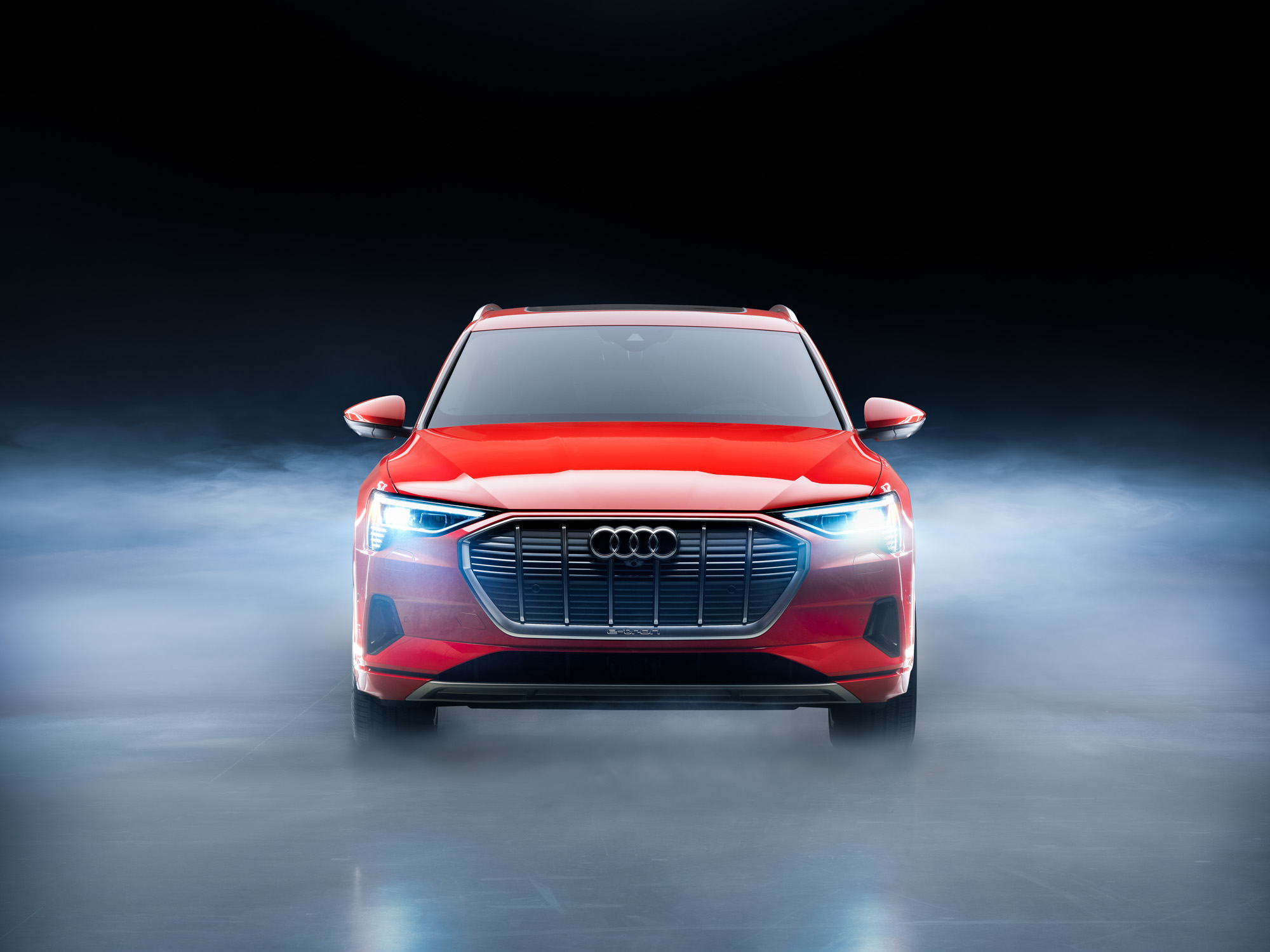 Front view of a red Audi SUV with headlights on, surrounded by mist on a dark background, captured in a futuristic style that evokes the eye of a fine artist.