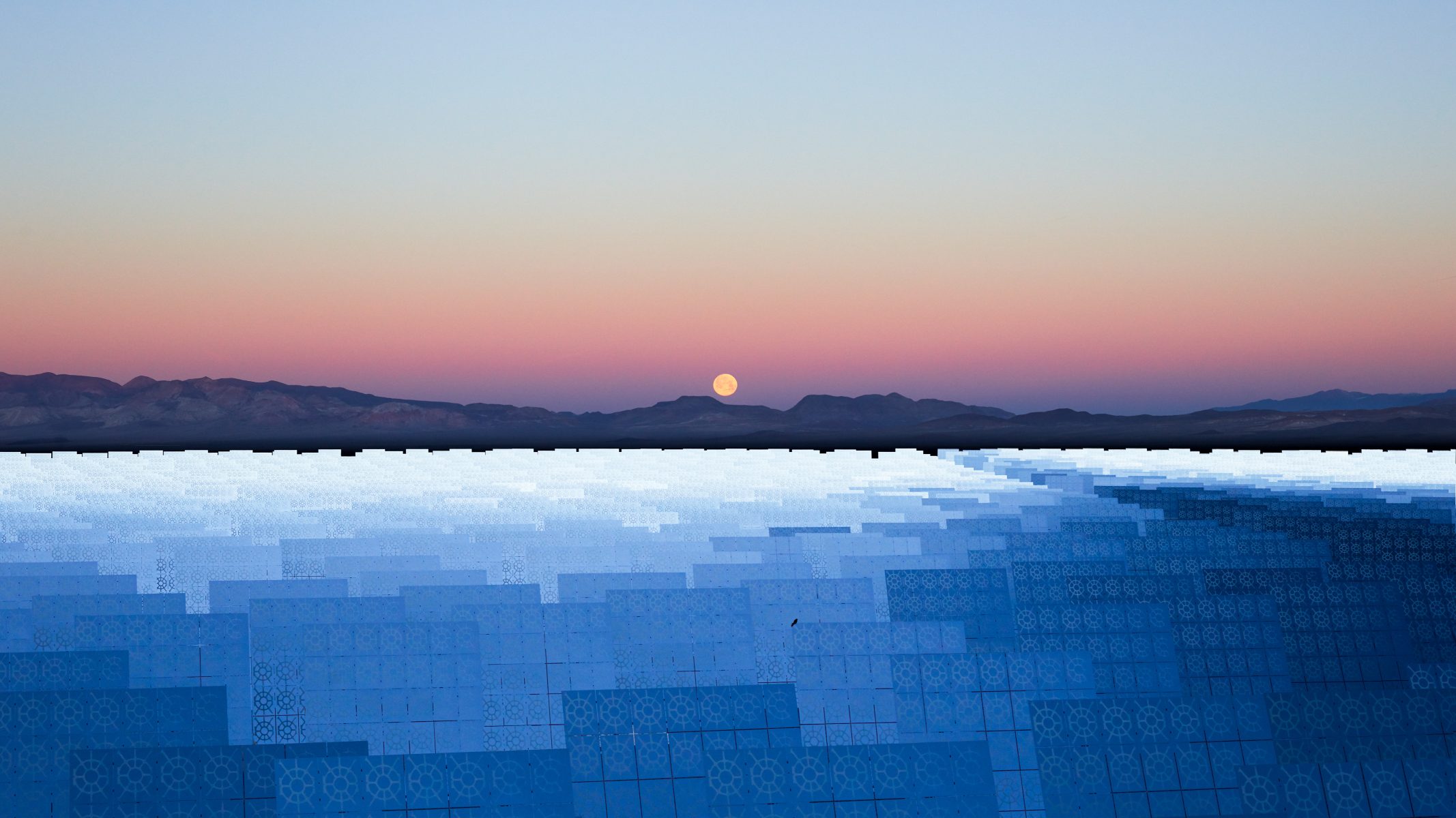 The full moon rises over distant mountains and a field of solar panels at sunset, as a photographer captures the scene enriched by mesmerizing drone light painting.