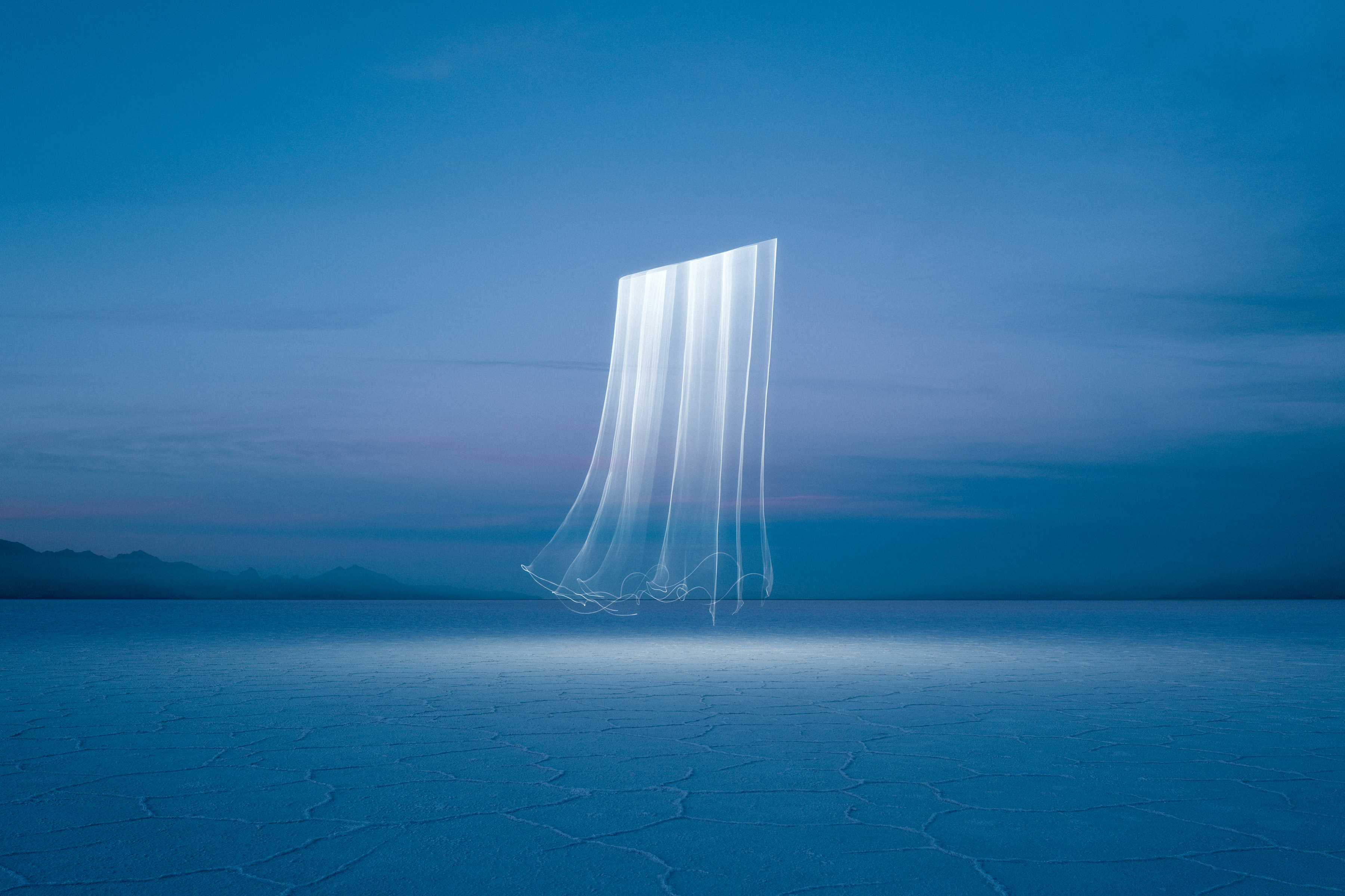 A glowing vertical light streak—reminiscent of drone light art—floats above a cracked, barren landscape under a twilight sky.