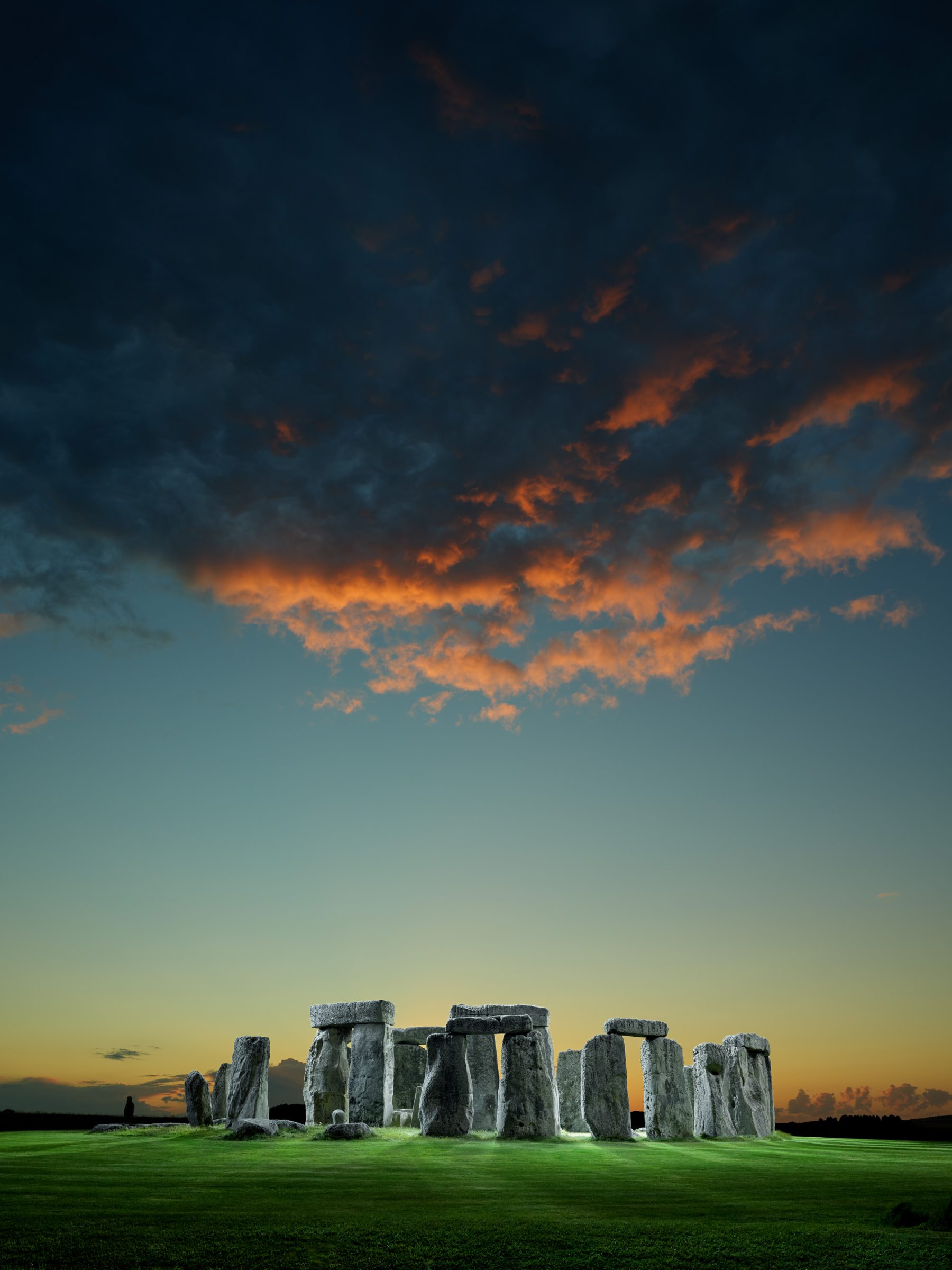 Stonehenge at sunset with dramatic clouds and orange light in the sky above the ancient stone monument, enhanced by mesmerizing drone light art captured by a skilled photographer.