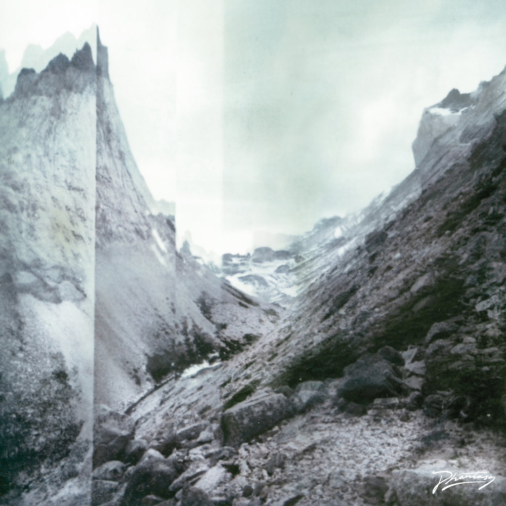 Rocky mountain landscape with jagged peaks, cloudy sky, and a signature in the bottom right corner—perfect for nighttime landscape photography by a skilled photographer.