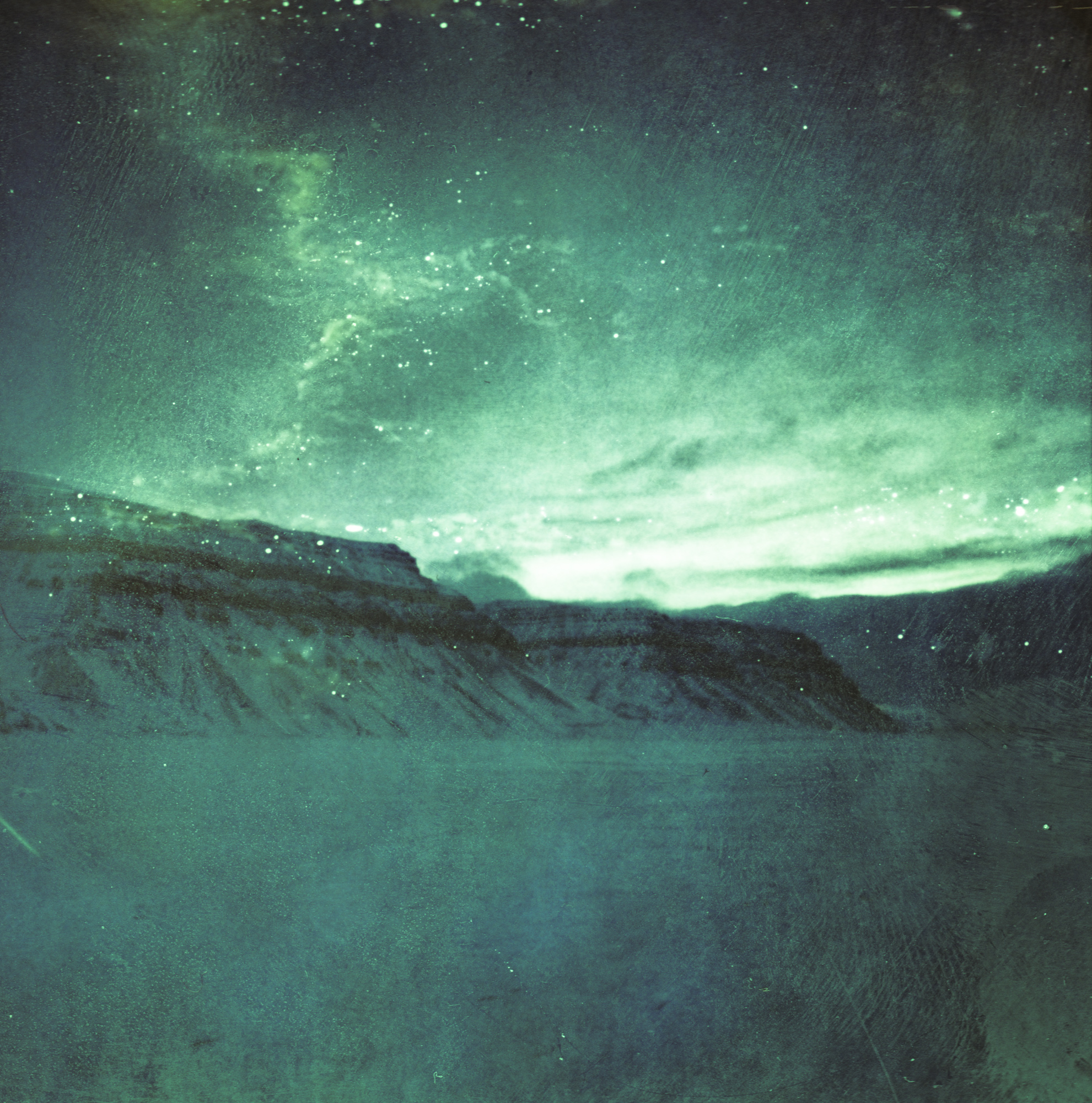 Aurora borealis glows over snowy mountains under a starry night sky as a photographer captures the scene, adding a touch of futuristic flair with dazzling drone light painting.