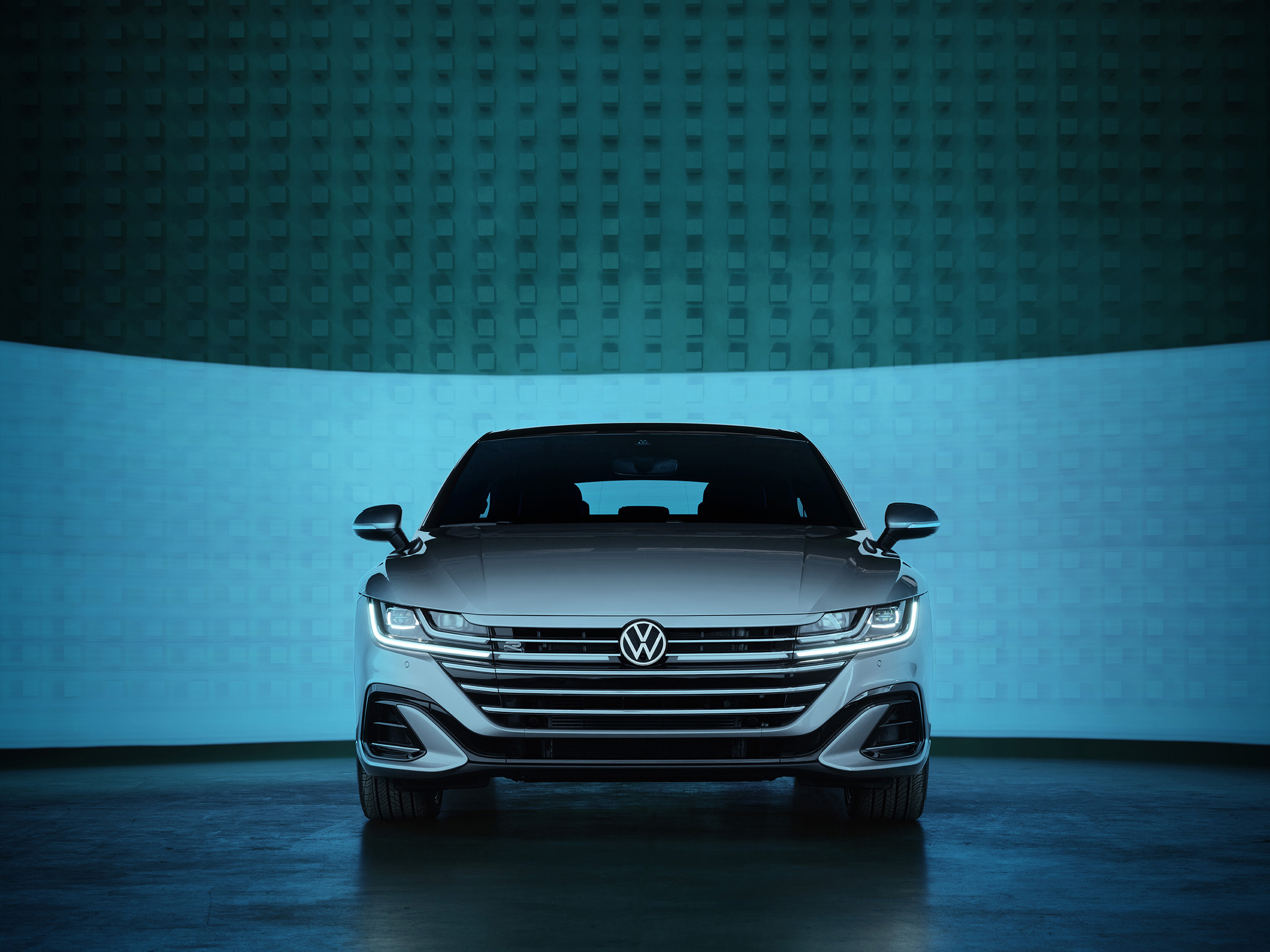 A silver Volkswagen sedan shown from the front against a blue-lit, modern background, captured with a photographer’s keen eye for nighttime landscape photography.