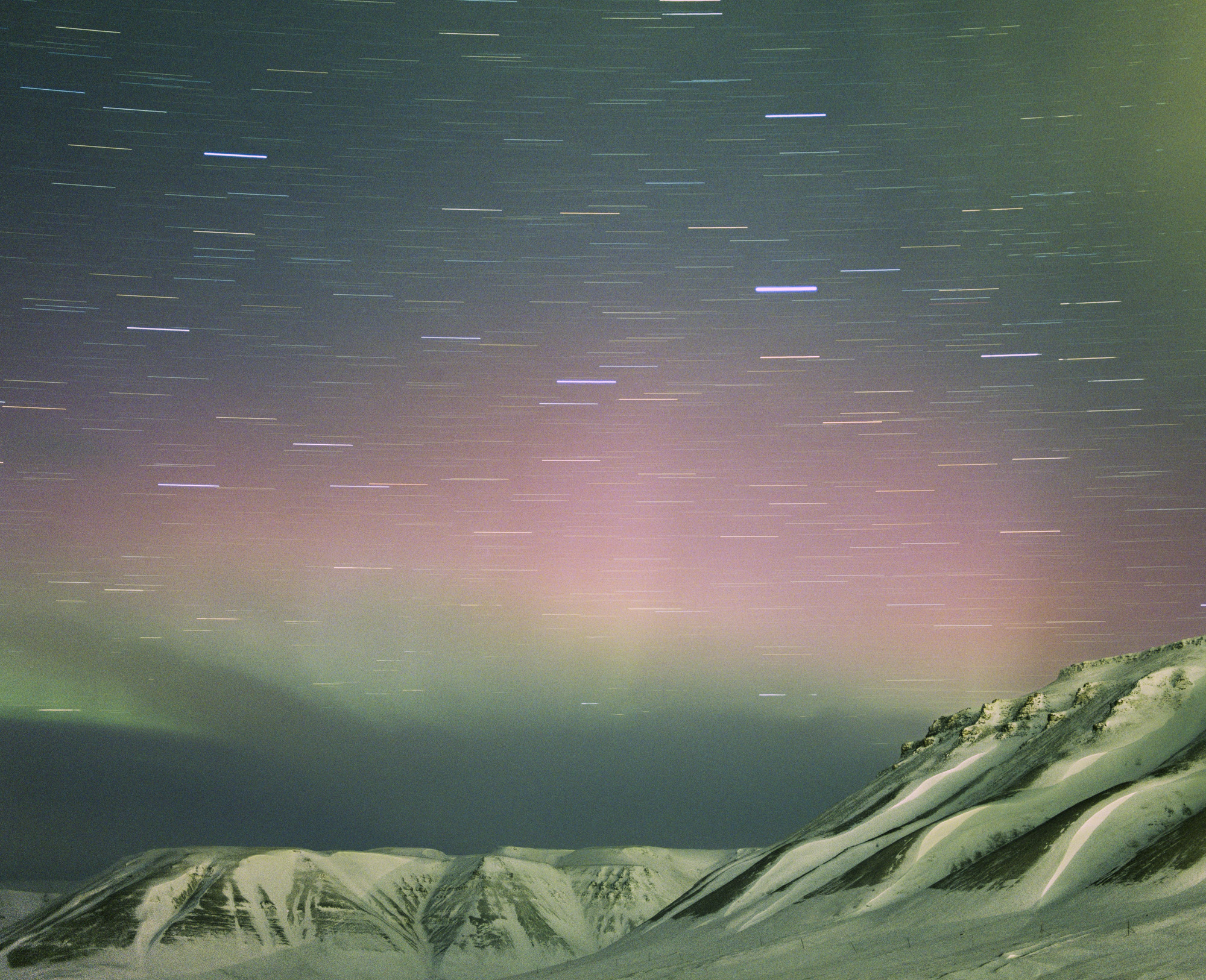 Futuristic aurora and star trails grace snowy mountains at night, with vibrant green and purple hues painting the sky—a stunning example of nighttime landscape photography.