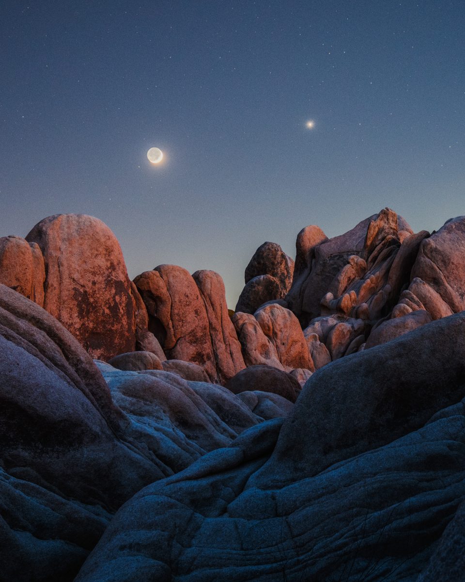 Large rocky formations rise under a twilight sky, where a crescent moon and a bright star shine—evoking the allure of fine artist nighttime landscape photography with a hint of futuristic mystery.