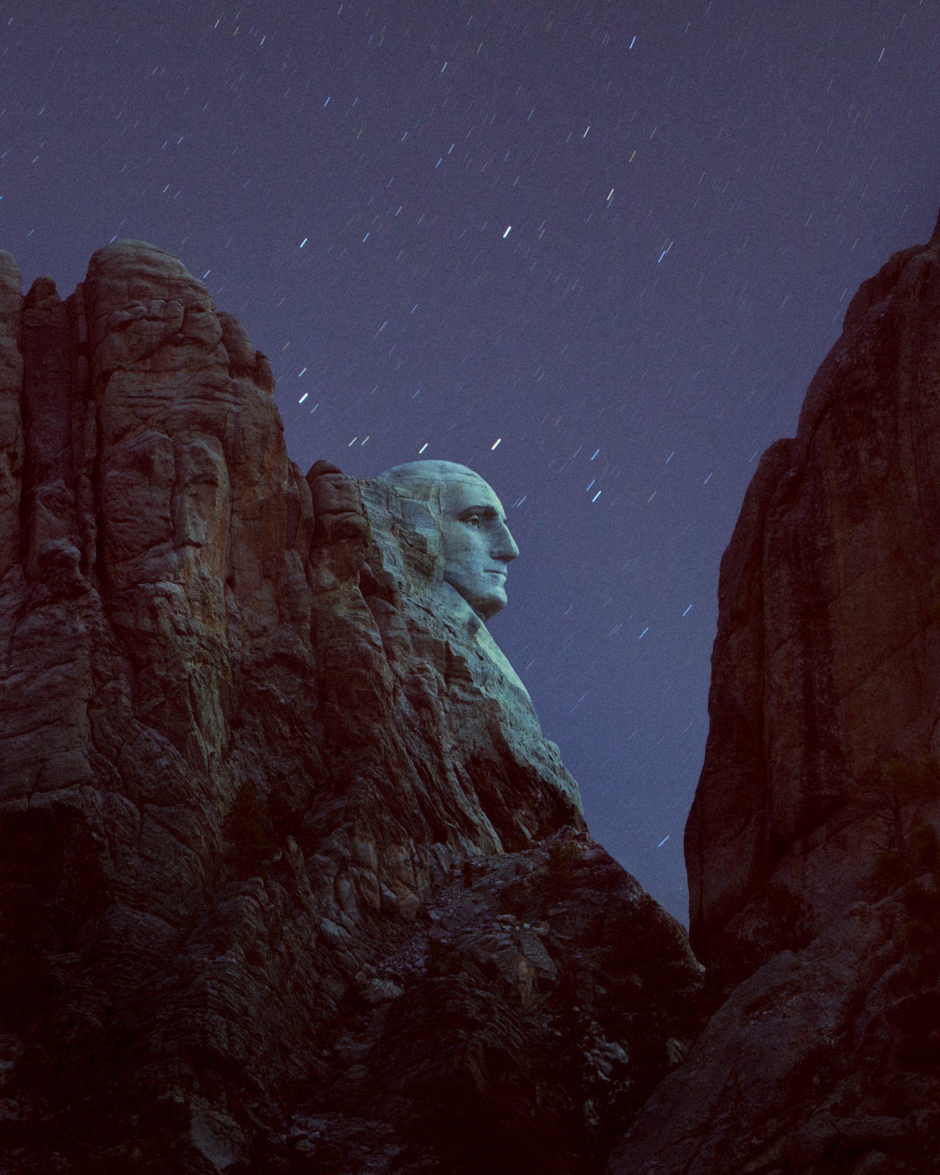 George Washington’s face on Mount Rushmore at night, surrounded by cliffs and a starry sky, is illuminated with futuristic drone light painting, creating a mesmerizing scene any photographer would love to capture.
