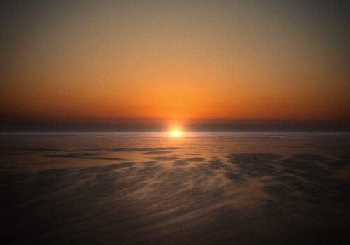 A serene sunset over the ocean, with warm orange and gold hues reflecting on calm water, captured by a skilled photographer specializing in nighttime landscape photography.