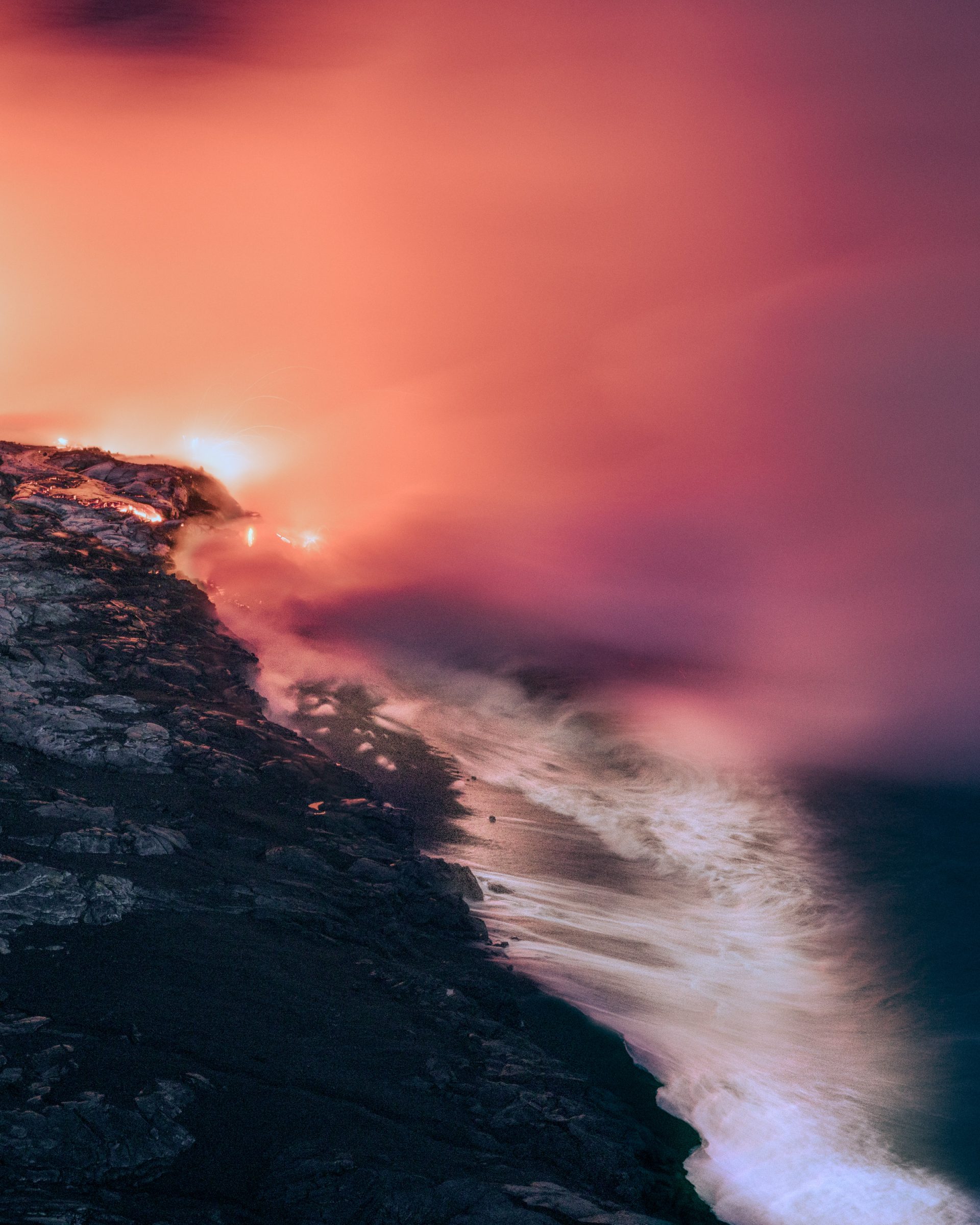 Lava flows into the ocean at dusk, creating steam and glowing orange light along a rocky shoreline—a scene any photographer or fine artist would find mesmerizing.