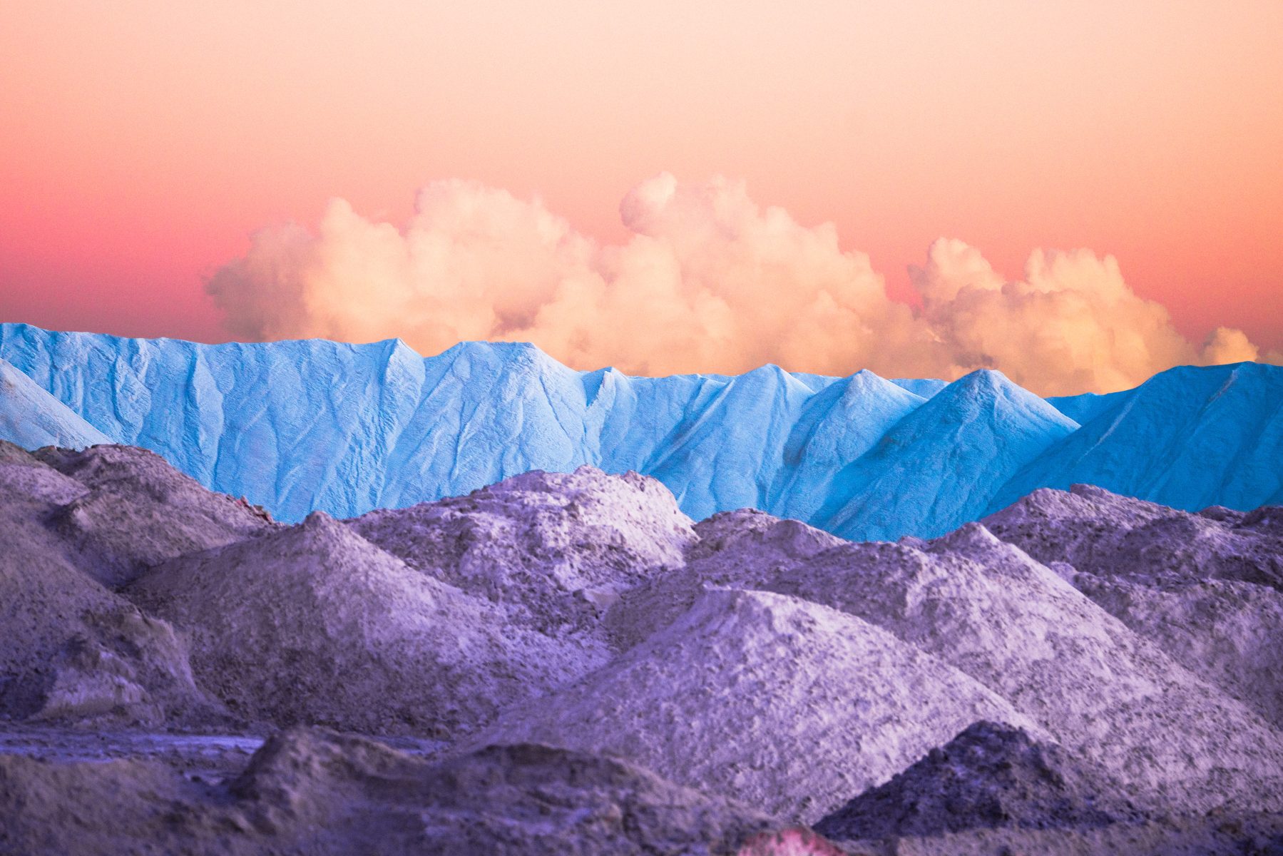 Lavender-hued hills and blue mountains under a pastel orange sky with fluffy clouds at sunset, captured by a photographer using drone light painting for a touch of futuristic artistry.