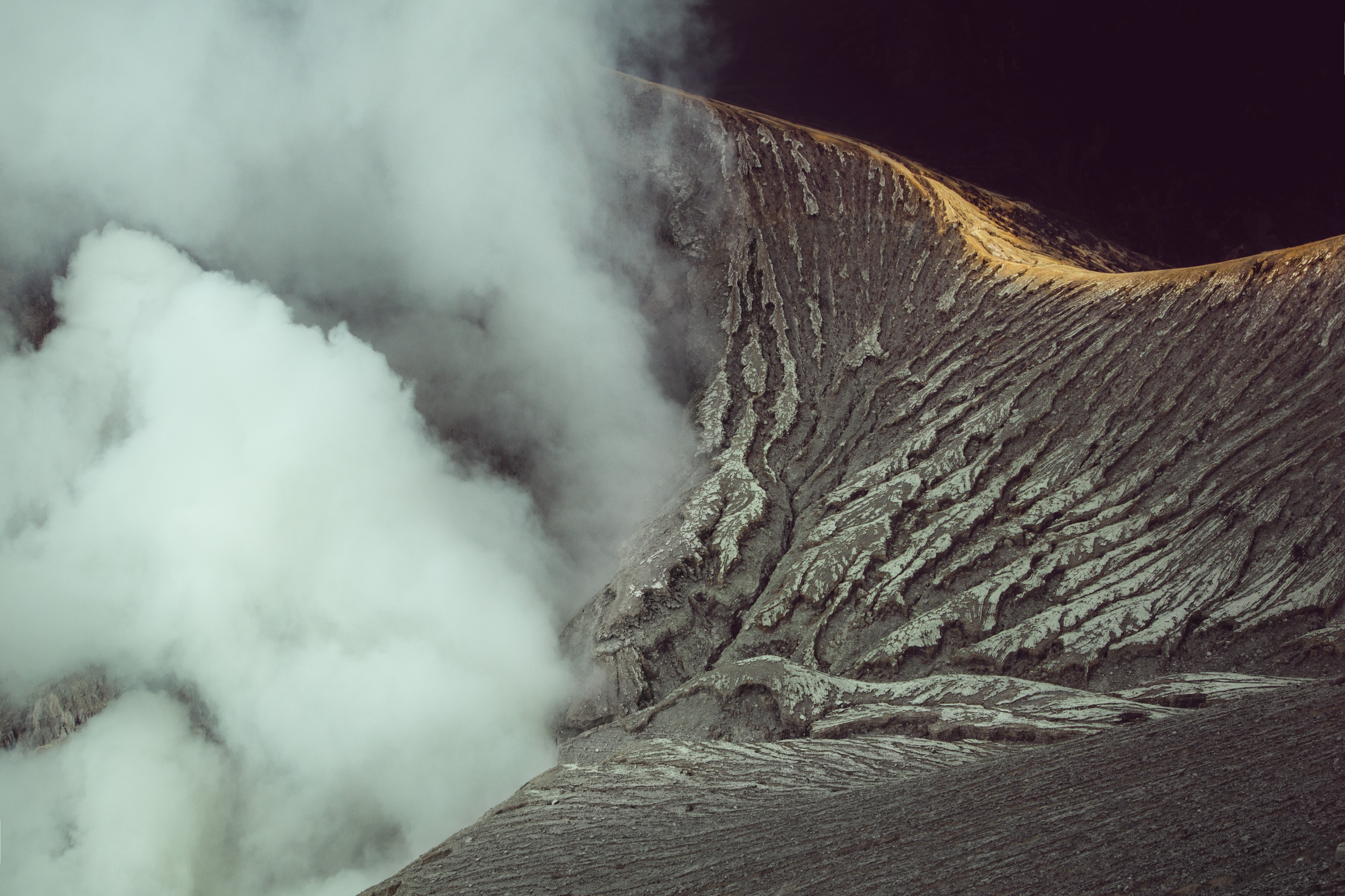 Thick white smoke billows from a rugged, textured volcano slope under soft lighting, as a photographer captures the scene enhanced by futuristic drone light art.