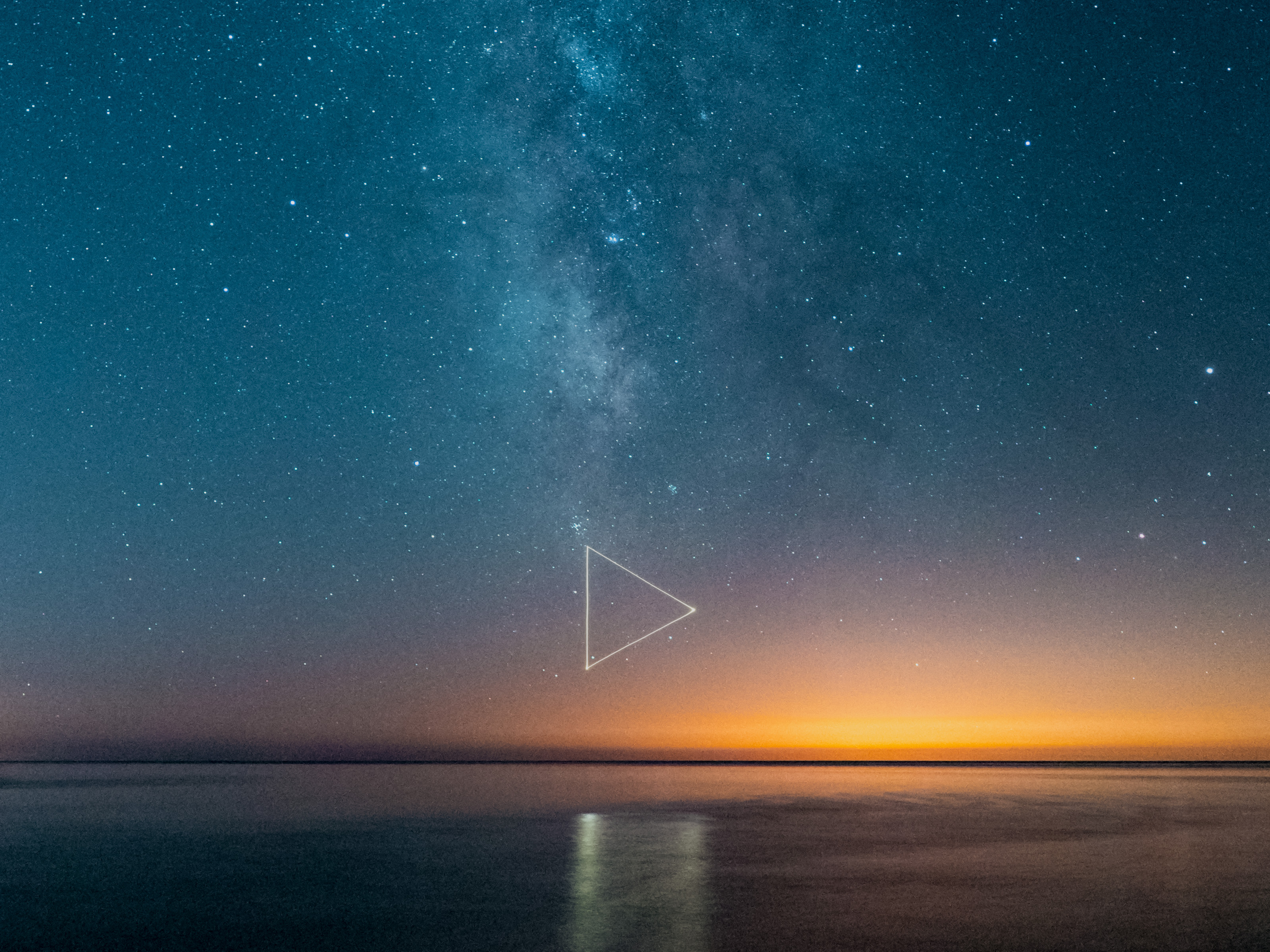 Milky Way and stars over calm water at sunset, captured in a nighttime landscape photography style, with a faint triangle symbol glowing in the sky.