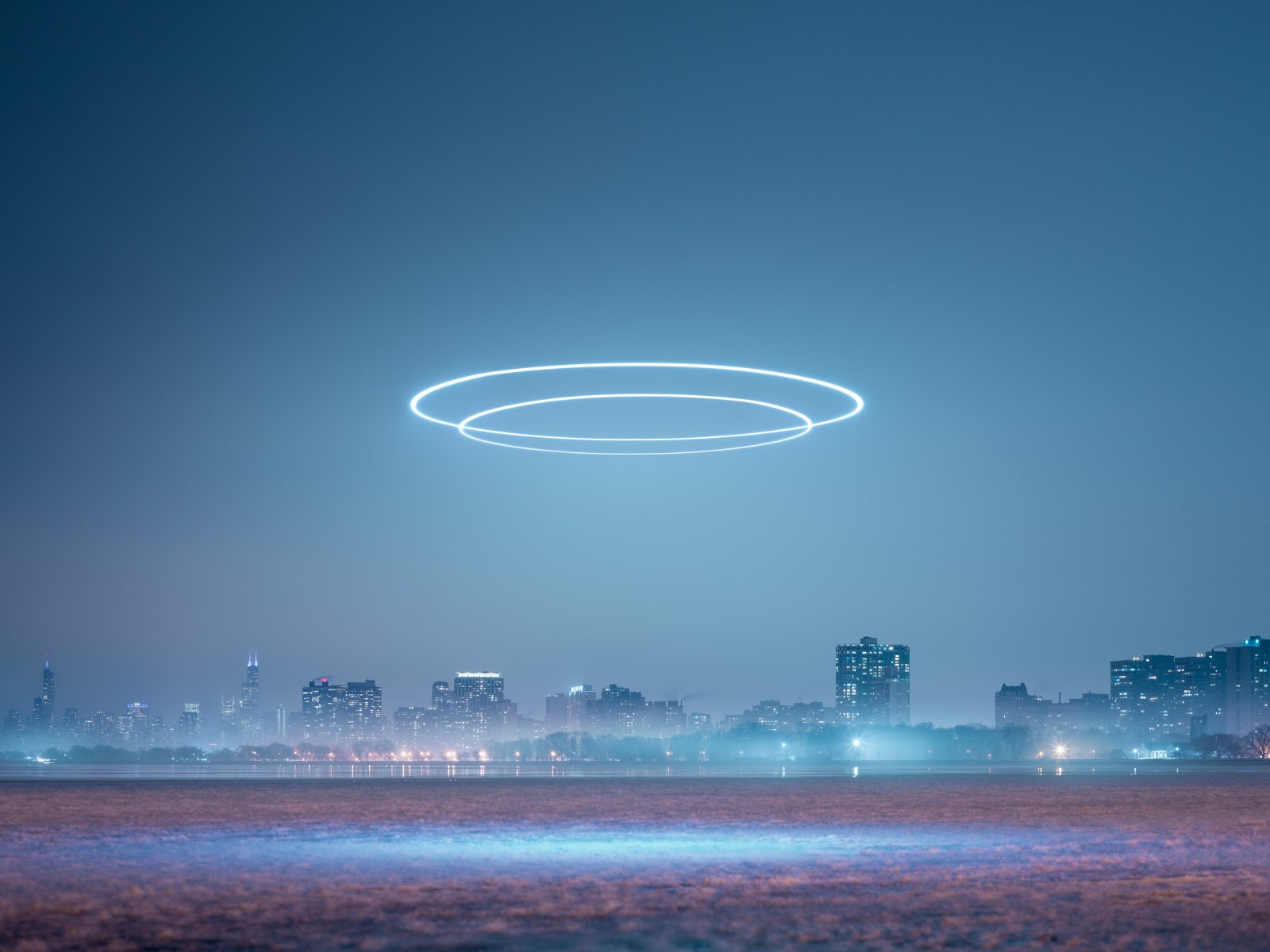 A city skyline at night with glowing drone light art rings illuminating the sky above the buildings.