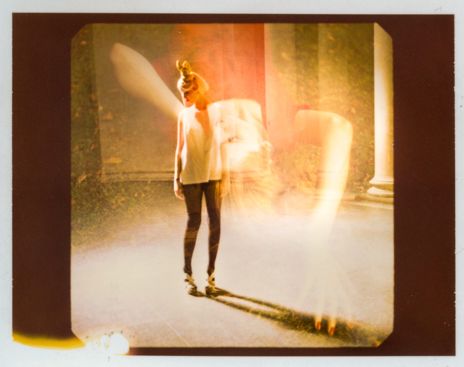 A fine artist stands in soft lighting with a double exposure effect, creating a ghostly, ethereal appearance reminiscent of drone light art.