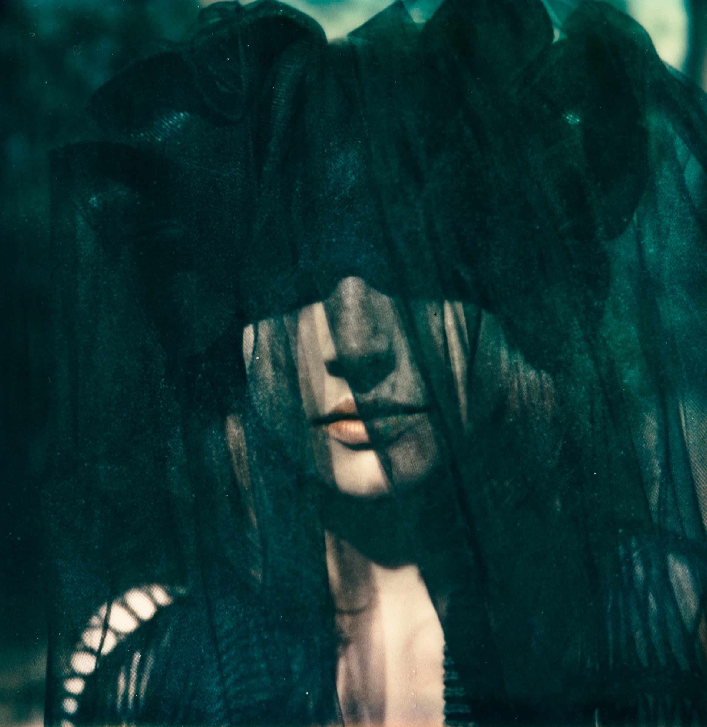 A woman with loose hair is draped in sheer black fabric, creating a mysterious and moody atmosphere, perfect for a fine artist or photographer seeking captivating inspiration.