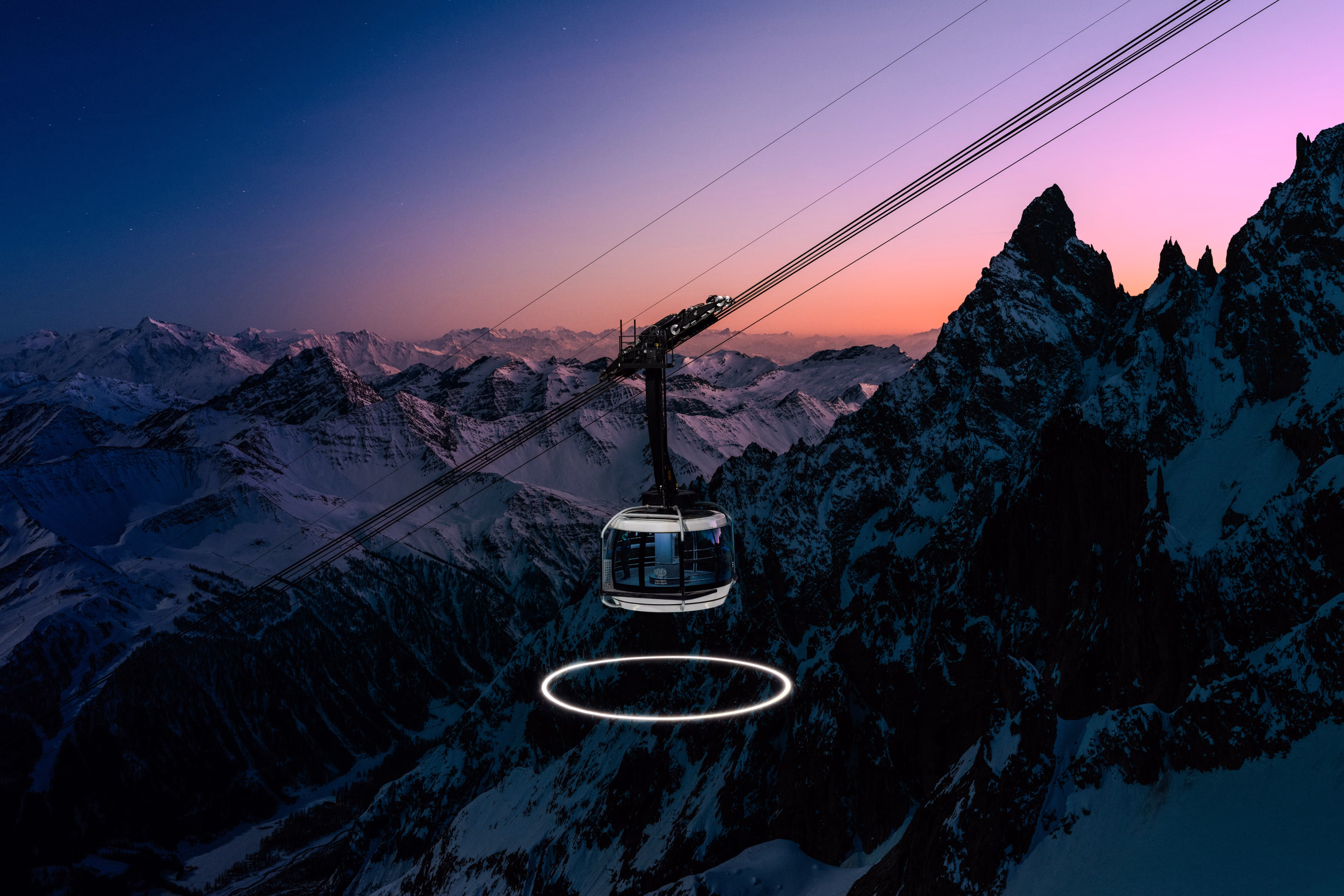 A cable car glides over snowy mountains at dusk, with a glowing circle visible below—capturing the serene beauty of the Skyway Monte Bianco on Mont Blanc.