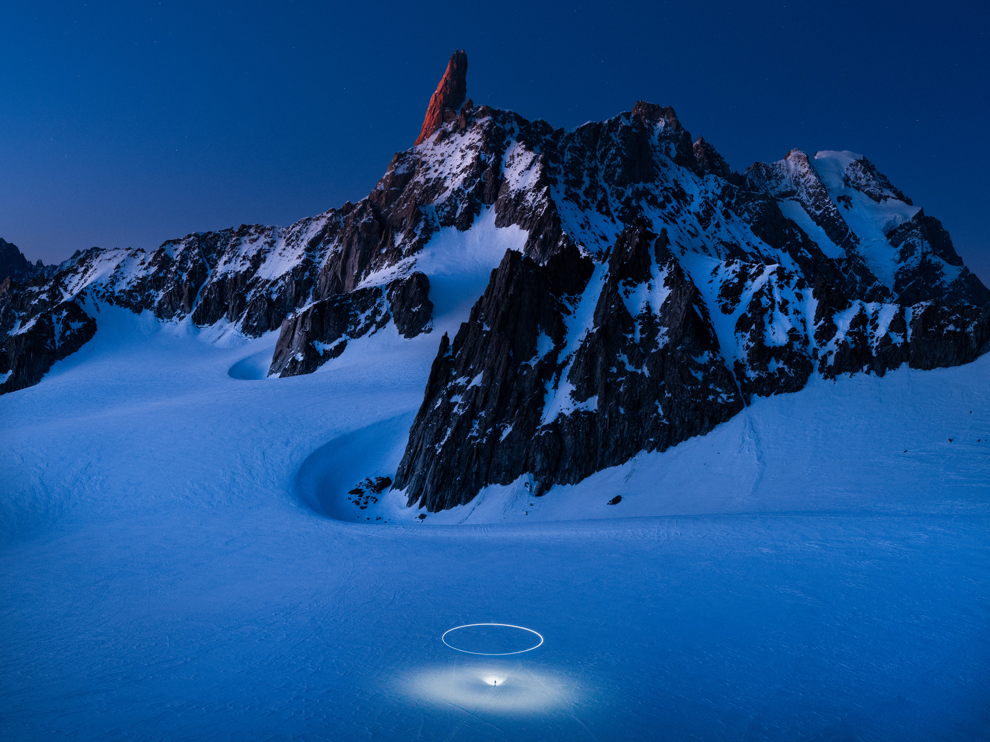 A snowy mountain illuminated by a mesmerizing drone light painting, creating a captivating glow in the heart of winter's landscape.